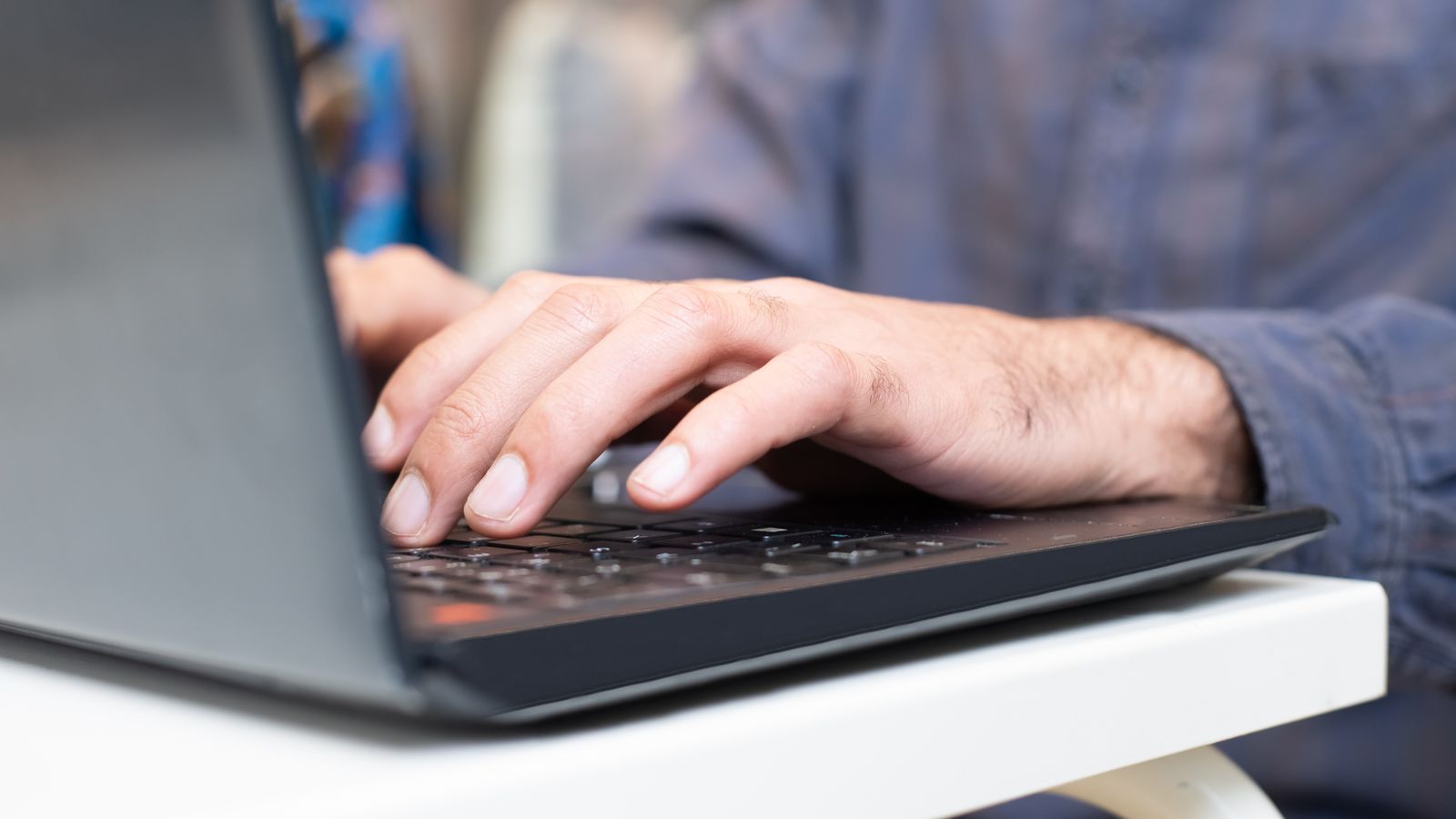 Dłonie wpisujące dane na klawiaturze laptopa