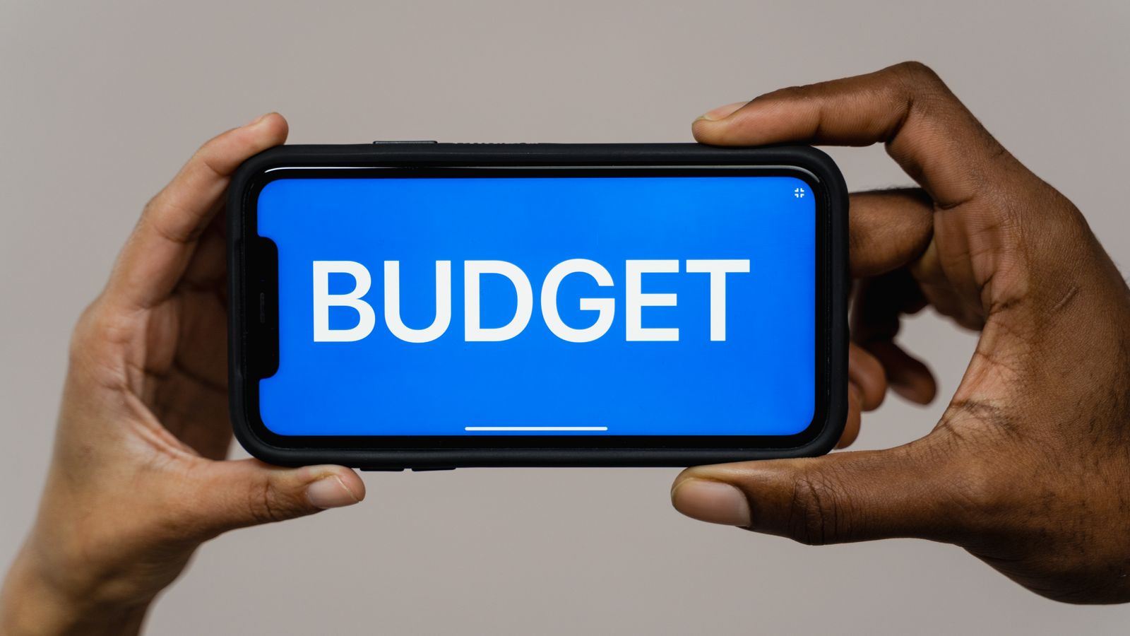 Dłonie trzymające telefon z napisem „budget” na ekranie
